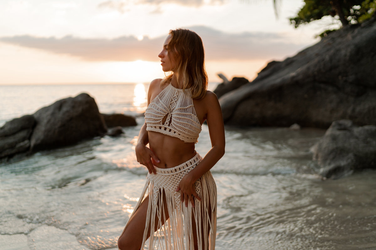Seductive woman  in white boho crochet dress posing on the beach. Summer and tropical vacation fashion photo.