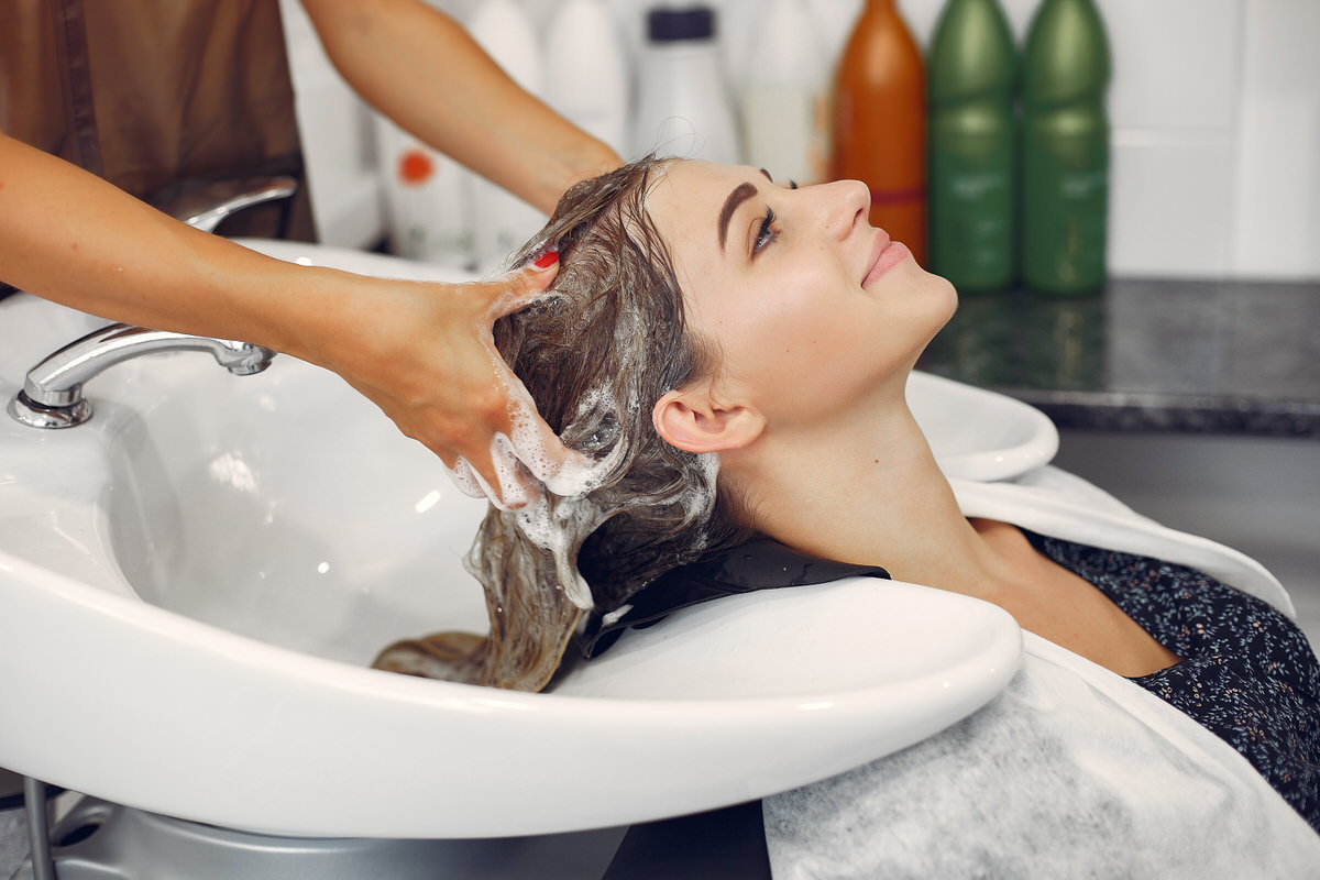 Woman washing head in a hairsalon Hairdresser washing head her client. Woman in a hair salon